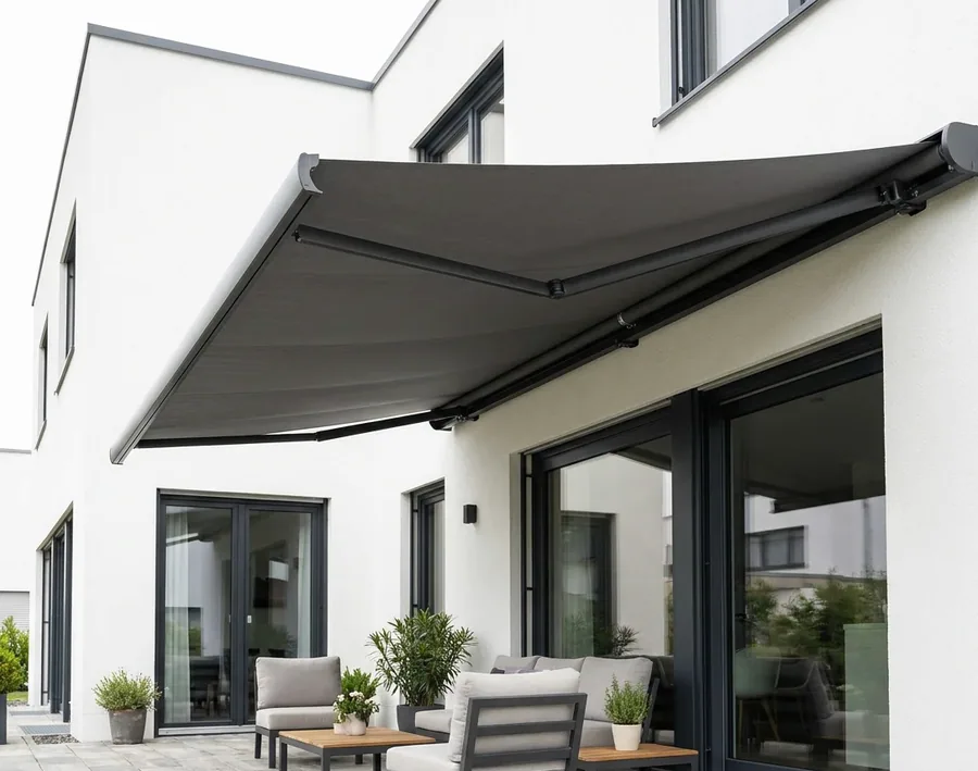 Folding-arm awning extended over a patio, its fabric canopy carried on hinged arms with no supporting posts